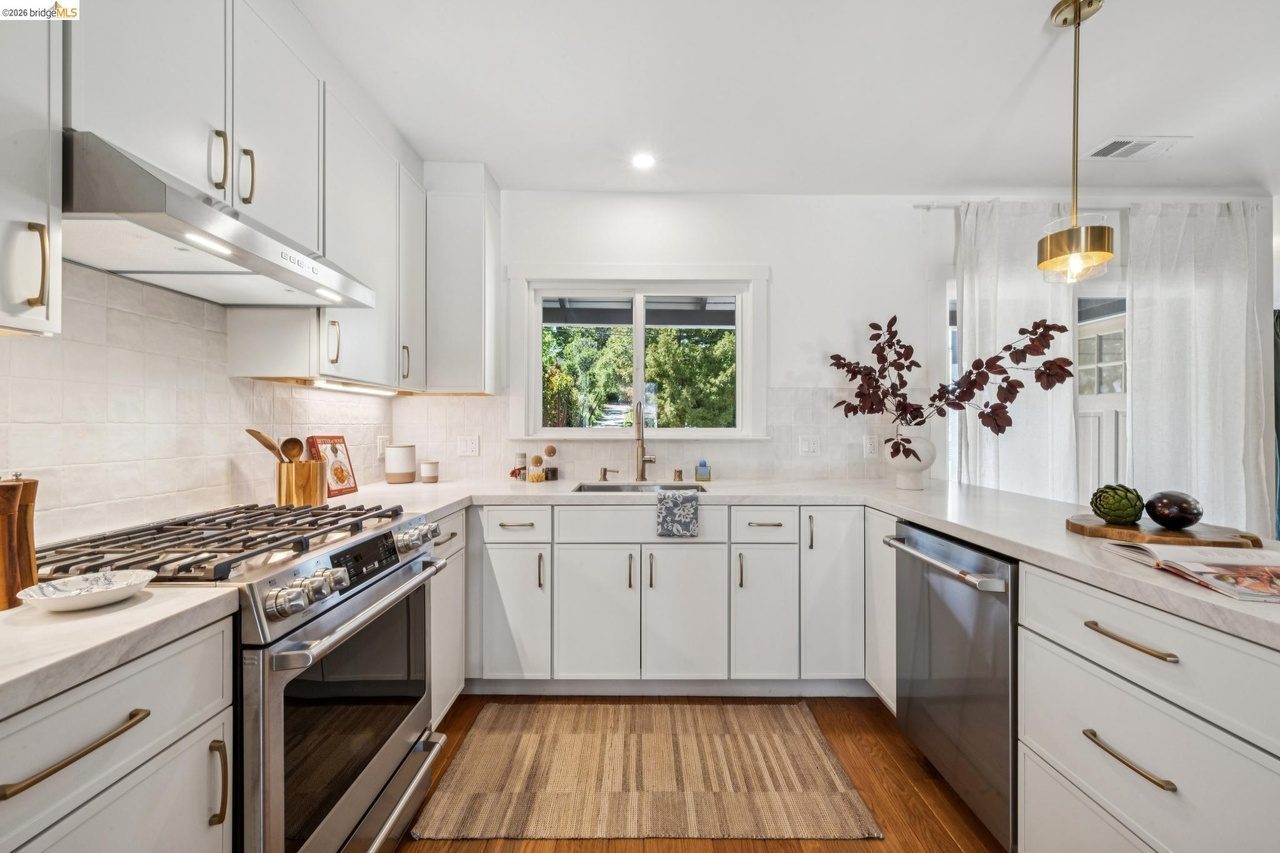 White kitchen with oak floors, quartz countertops with champagne bronze finish