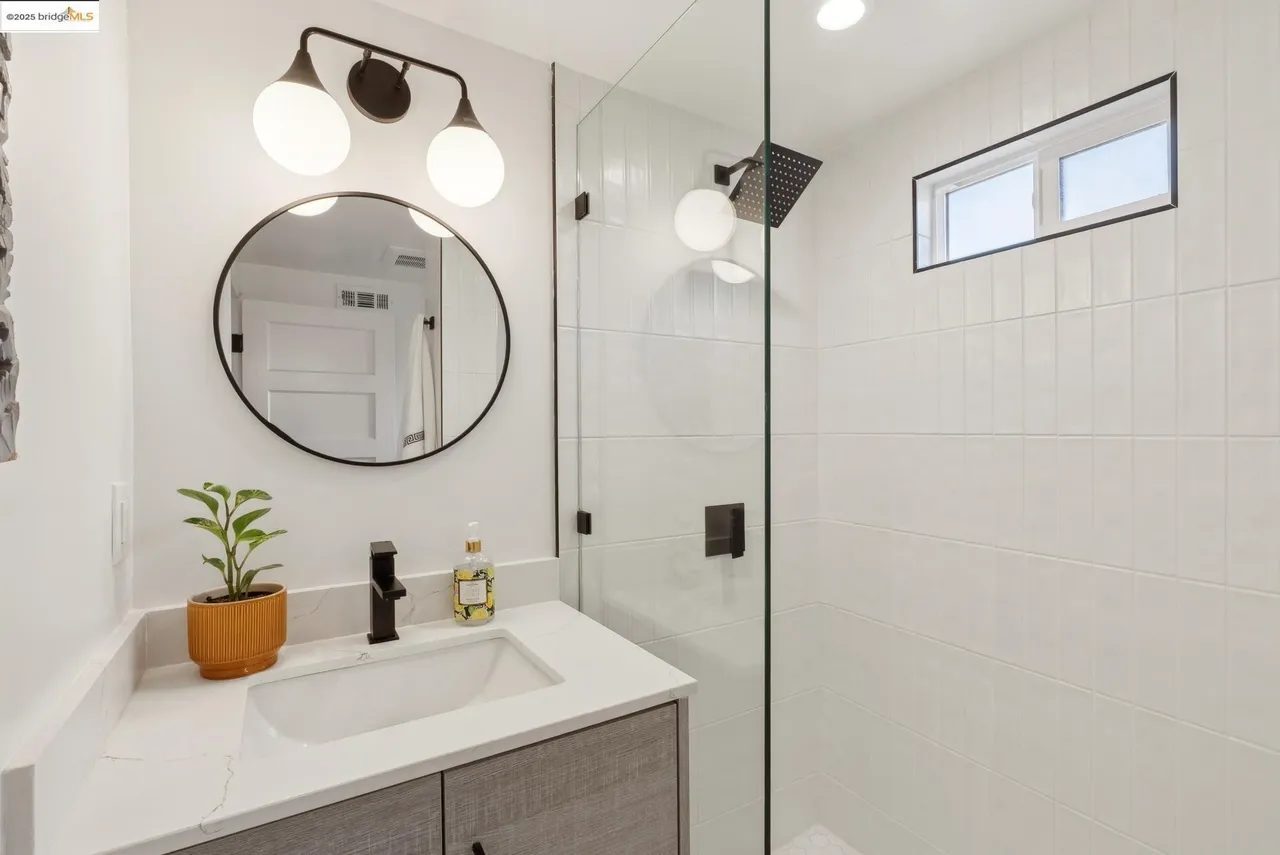 Bathroom with vanity and glass door leading to shower, white tile with black fixtures